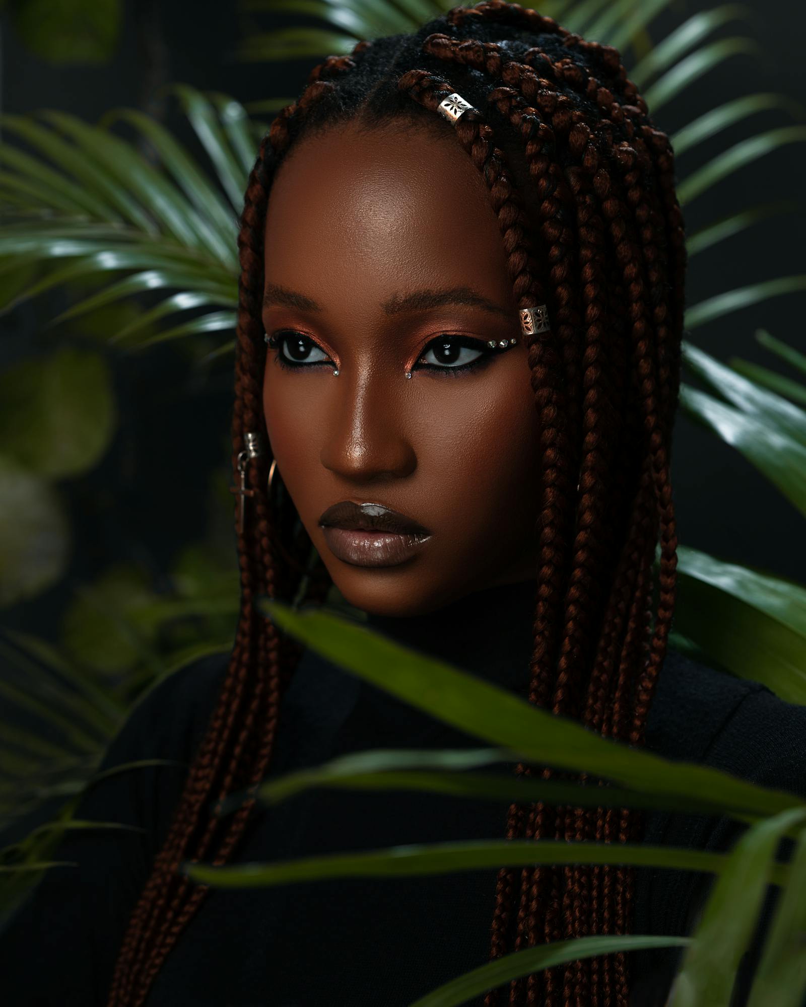 A client with long auburn box braids and gold cuffs
